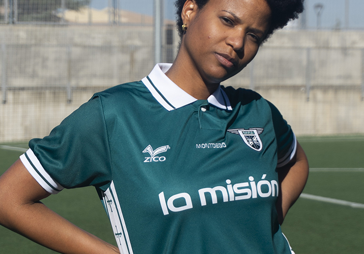 Fotografía de moda Montdebó | Camiseta Fernando Alonso Modelo femenina con camiseta verde de Montdebó inspirada en Fernando Alonso, fotografiada en un campo de fútbol.