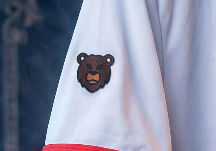 Fotografía de detalle de camiseta Montdebó | Oliver Bearman Detalle de un oso bordado en una camiseta blanca con ribete rojo de la colección Oliver Bearman de Montdebó.